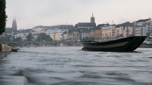 Boat in river against sky in city