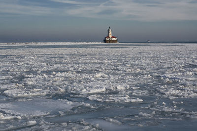 Lighthouse by sea against sky