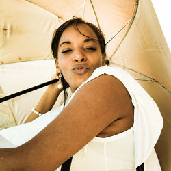 Portrait of woman puckering lips while holding umbrella outdoors