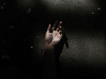 Cropped hand of woman lying on ground at night