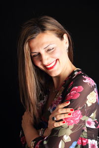 Close-up of smiling young woman against black background