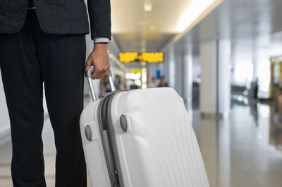 Midsection of businessman with suitcase at airport