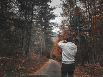 Rear view of man standing on road in forest