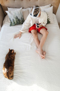 Boy in vr headset with tabby cat on bed, cozy setting.