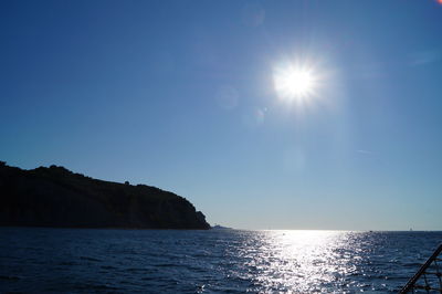 Scenic view of sea against blue sky on sunny day