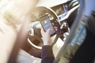 Man in car adjusting devices at home via smartphone