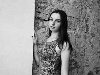 Portrait of beautiful young woman standing against wall