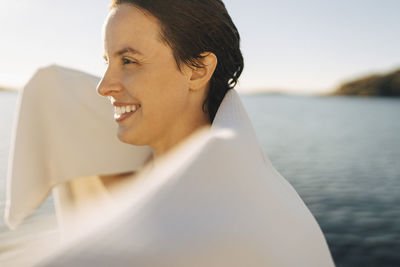 Happy woman drying hair with towel at sunny day