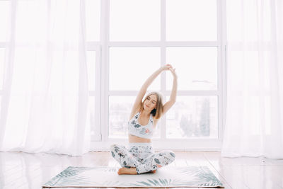 Girl in a sports uniform does exercises, physical exercises, yoga and stretches at home