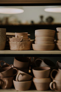 Shelves with ceramic dishware in pottery workshop