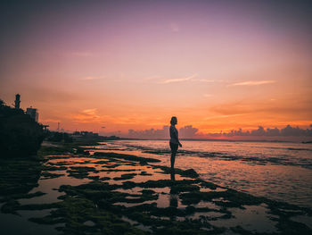 Silhouette man standing on beach against sky during sunset