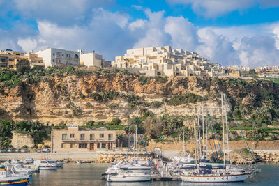 Sailboats moored on sea against buildings in city