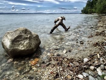 Full length of man on rock at beach against sky