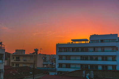 Buildings in town against sky during sunset