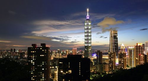 Illuminated buildings in city against sky at night