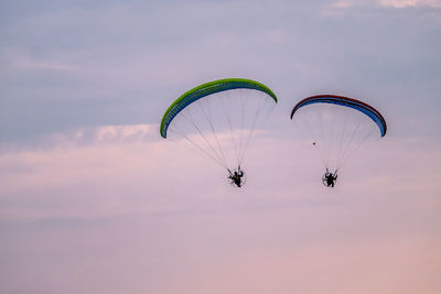 Person paragliding against sky during sunset