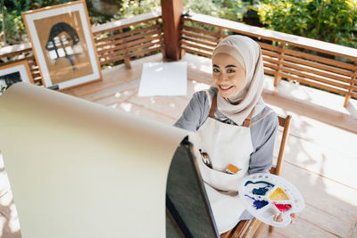 Portrait of smiling young woman sitting on table