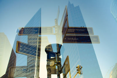 Double exposure of information sign and building against clear blue sky in city