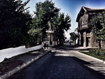 Street amidst buildings and trees against sky