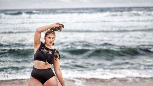 Portrait of young woman standing at beach