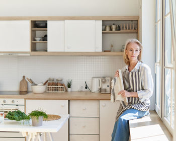 Senior woman sitting by window at kitchen