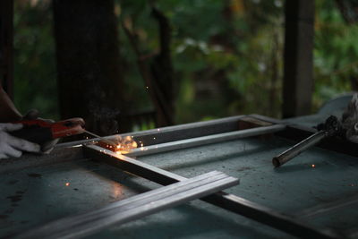 Cropped hands of man welding metal on workbench in workshop