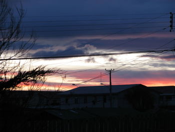 Silhouette electricity pylon against sky during sunset