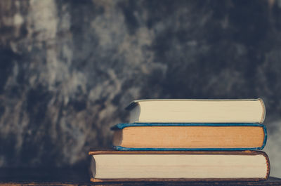 Close-up of books on wooden table against wall