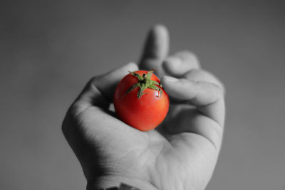 Close-up of hand holding strawberry over white background