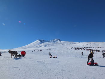 People on snowcapped mountain against clear sky