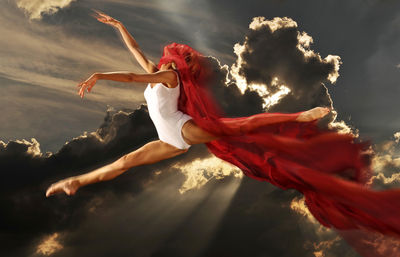 Side view of woman dancing against sky