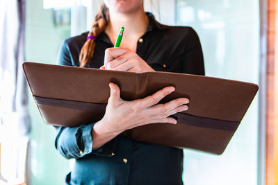 Midsection of woman holding file