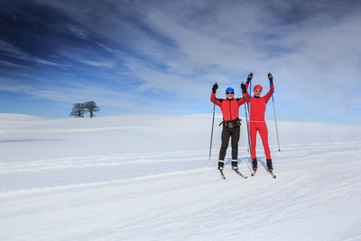 People skiing on snowy field against sky