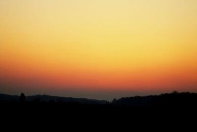 Scenic view of silhouette landscape against orange sky