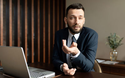 Salesman gesturing while sitting at desk in office