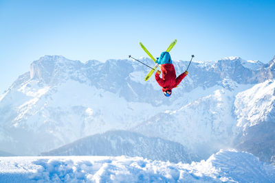 Man skiing on snowcapped mountain against sky