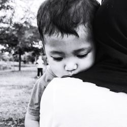 Rear view of mother carrying son while standing at park