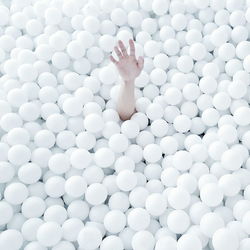 Cropped image of hand emitting from white ball pool