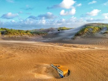 Scenic view of sand dunes at beach against sky