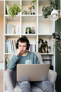 Young woman using laptop while sitting on sofa at home