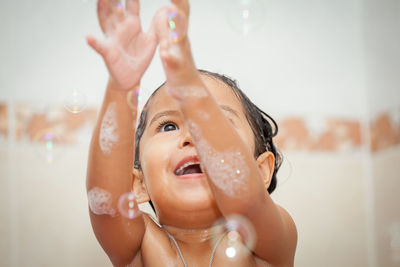 Close-up of shirtless girl playing with bubbles in bathroom