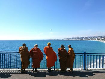 Rear view of people looking at sea against clear sky