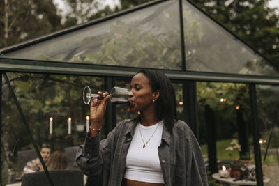 Smiling woman drinking wine in garden