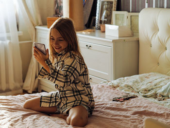 Young woman sitting on bed at home