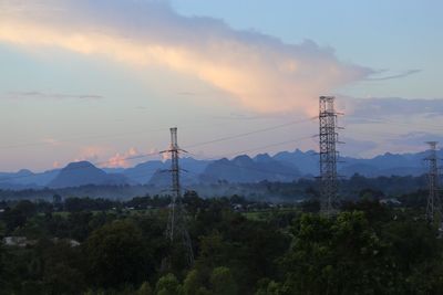 Electricity pylon on mountain against sky during sunset