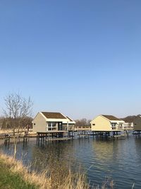 Houses by buildings against clear blue sky