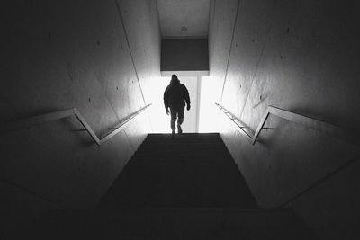 Rear view of silhouette man standing on staircase in building