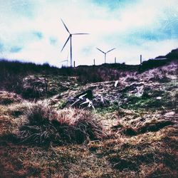 Windmills on field against sky