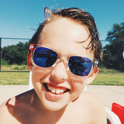 Portrait of smiling boy wearing sunglasses against sky