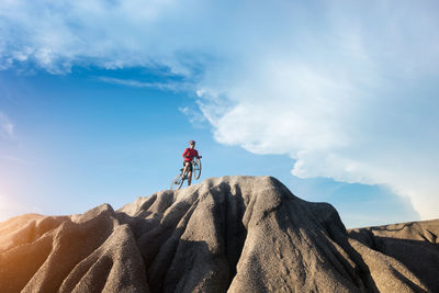 Low angle view of people riding on rock against sky